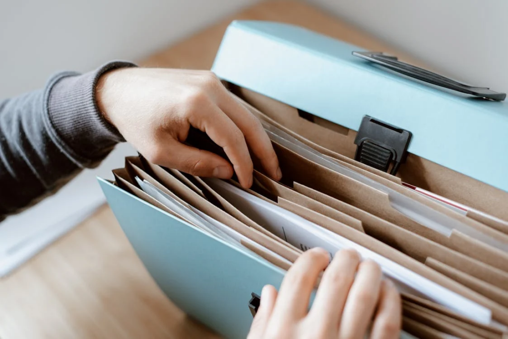 A person holds a file folder filled with papers, symbolizing the importance of documenting interactions with debt collectors.