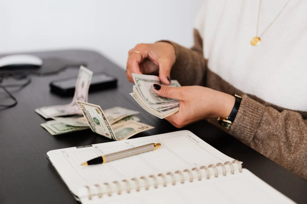 A woman meticulously counts her money at a desk, symbolizing the financial struggles prevalent in American households.