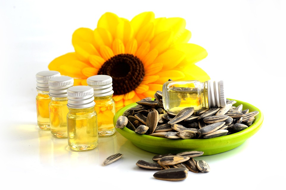 Sunflower oil and seeds arranged with a bowl of seeds, illustrating the need for balanced omega-6 and omega-3 fatty acids in diets. Sunflower oil is one of the worst foods for arthritis due to its high omega-6 content.