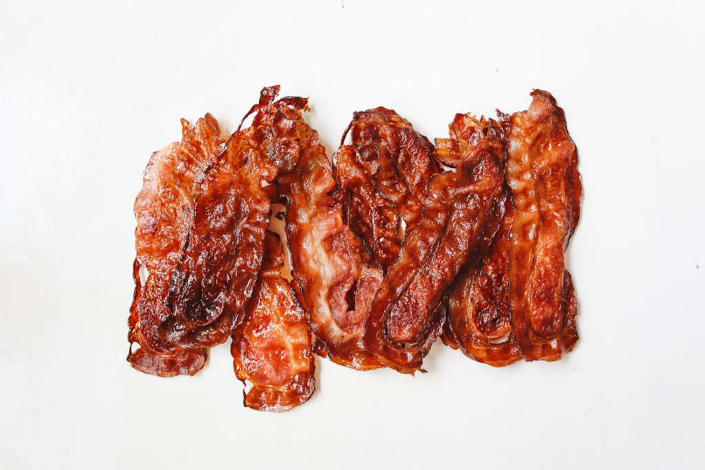 Slices of bacon arranged on a white surface, highlighting a tempting yet potentially harmful food for arthritis sufferers.