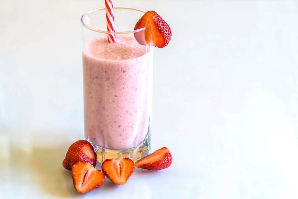 A strawberry smoothie with a straw, made with dairy; which is one of the worst foods for arthritis