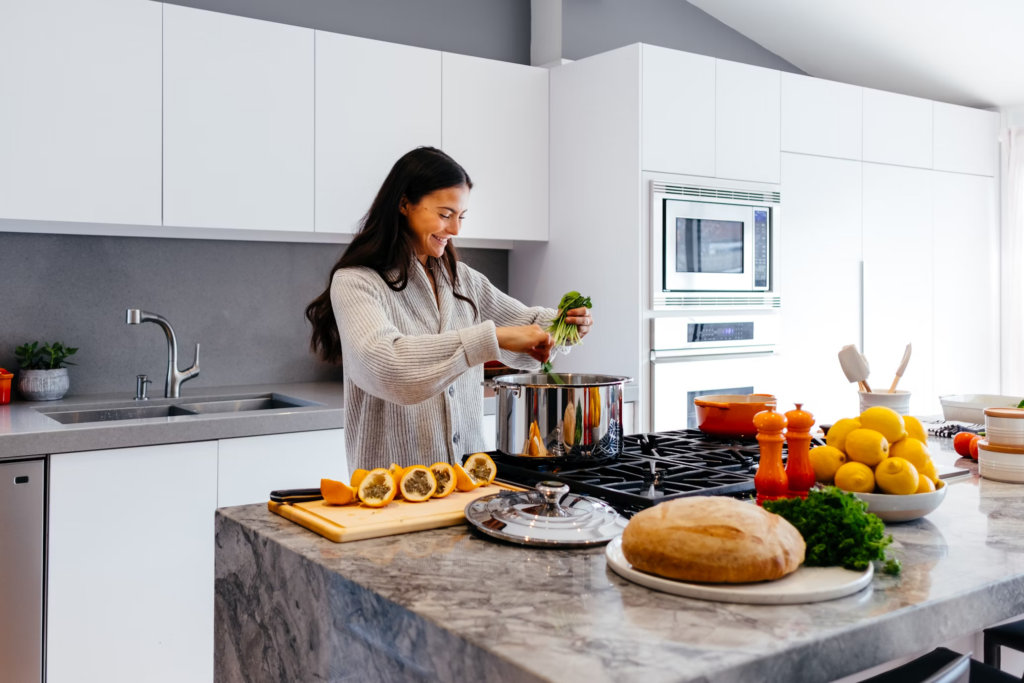 A woman prepares a variety of healthy dishes in a well-stocked kitchen filled with fresh ingredients.
