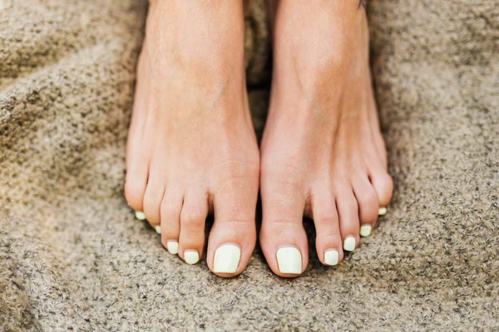 A close-up of a woman's well-groomed feet with white nail polish, highlighting healthy toenails and proper care.