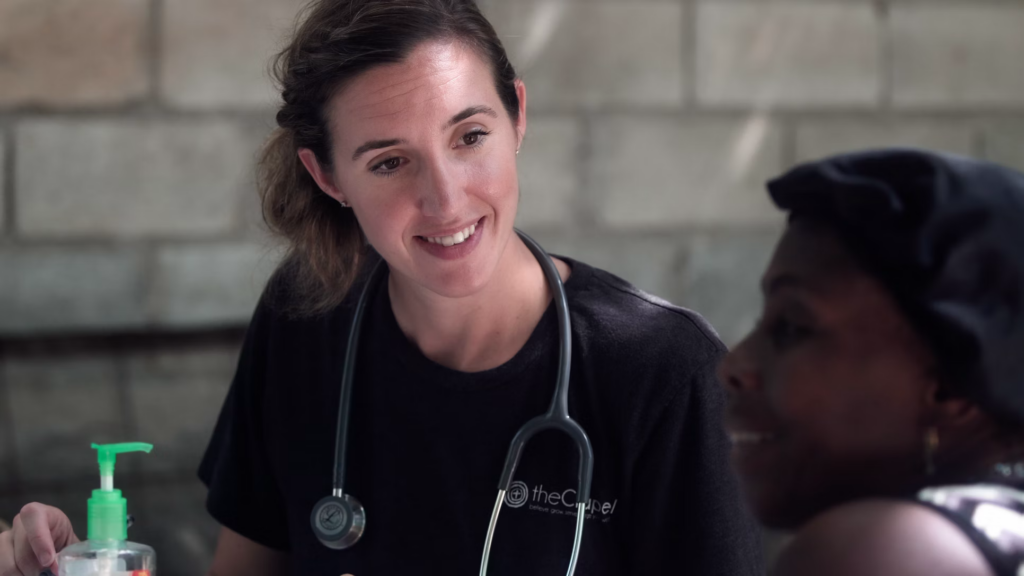 A doctor in a black shirt smiles while discussing thick toenails with a concerned patient.