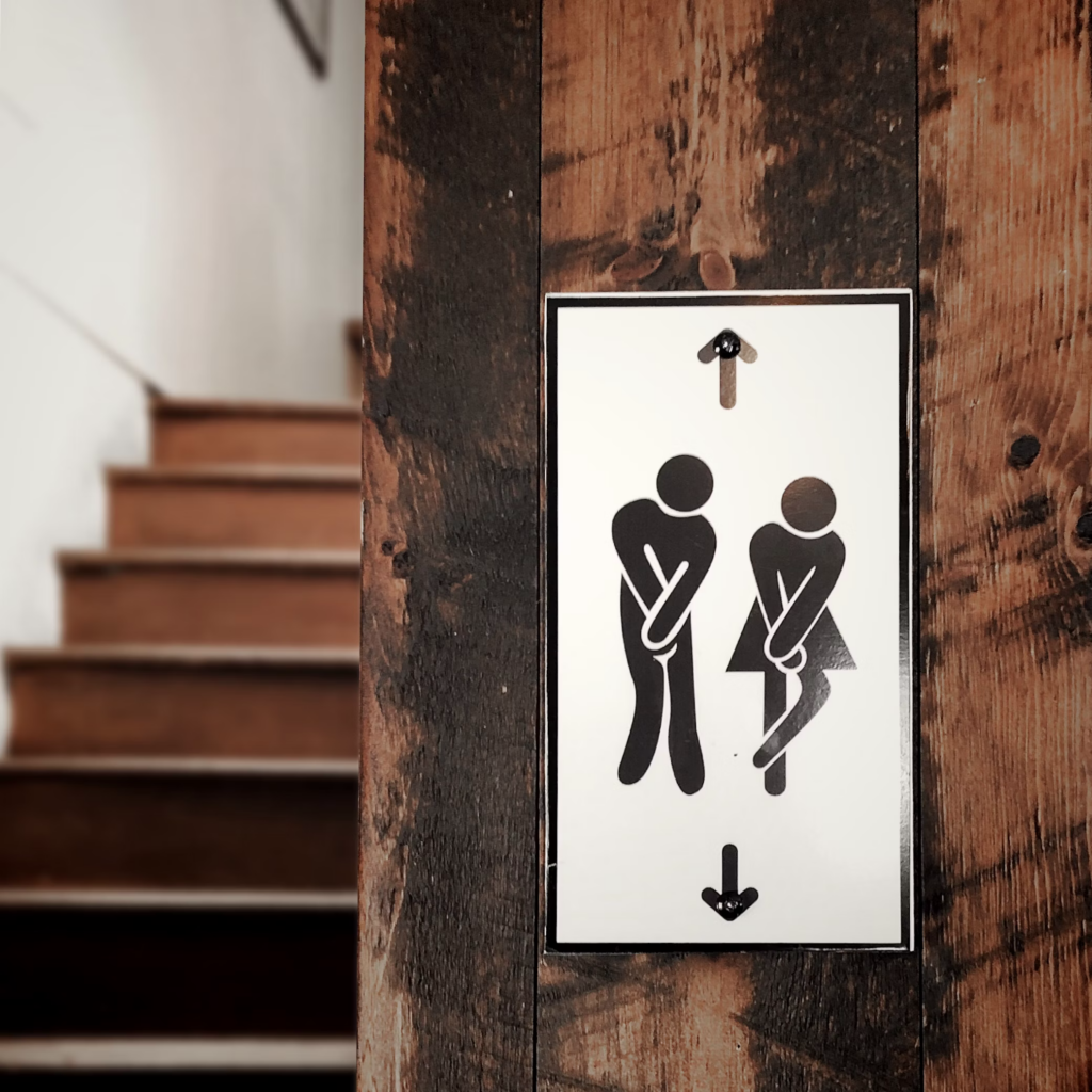 Sign for men's and women's restrooms, emphasizing the connection between colon health and regular bathroom breaks.