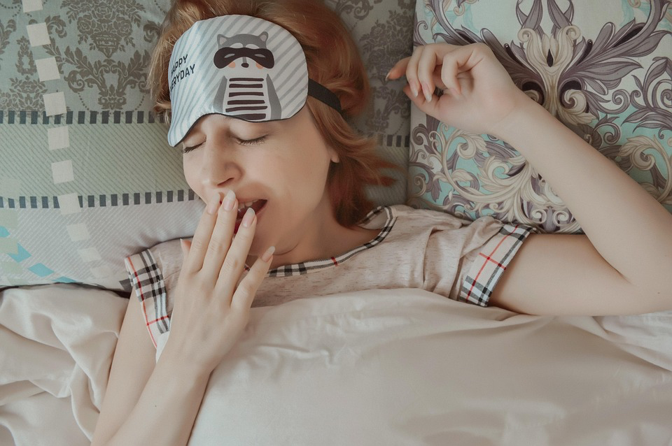 A woman is sleeping with a mask on, emphasizing the need to pay attention to fatigue that lingers despite rest.