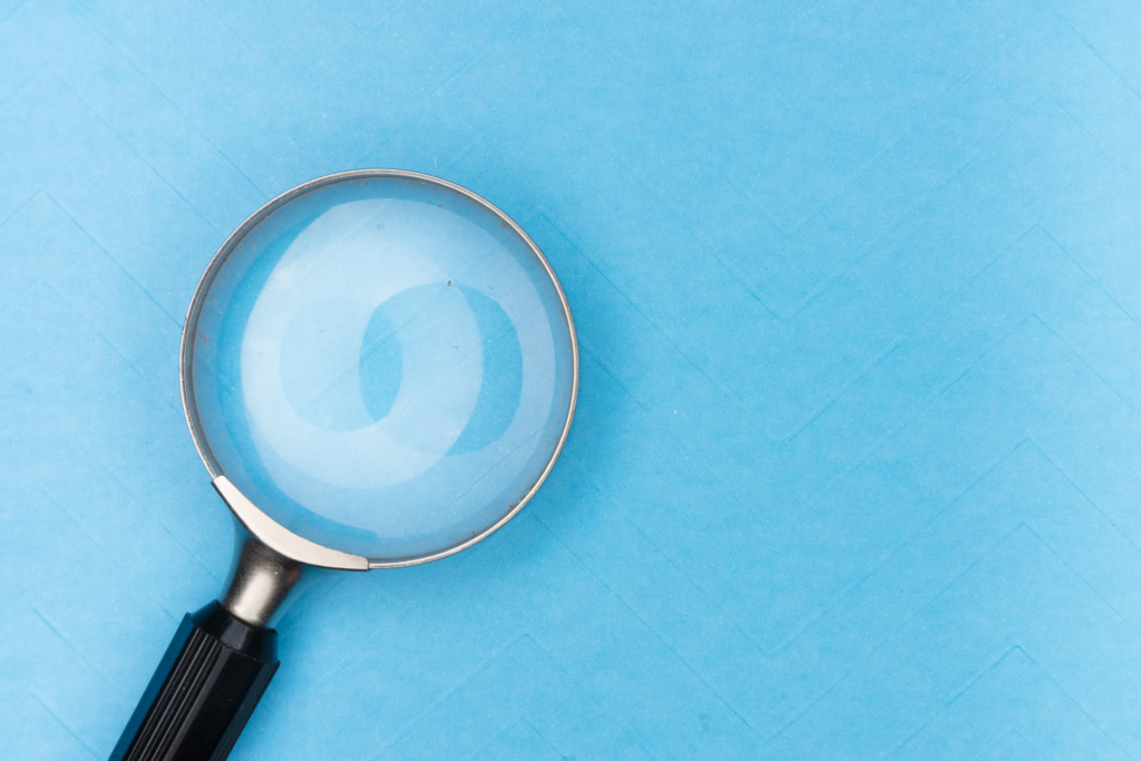 A magnifying glass resting on blue paper, symbolizing the importance of early detection in colon cancer for better survival rates.