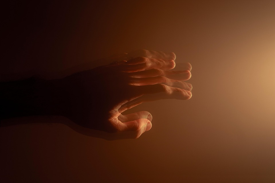 Close-up of a visually distorted hand reaching out, set against a warm, gradient background transitioning from dark to light orange.