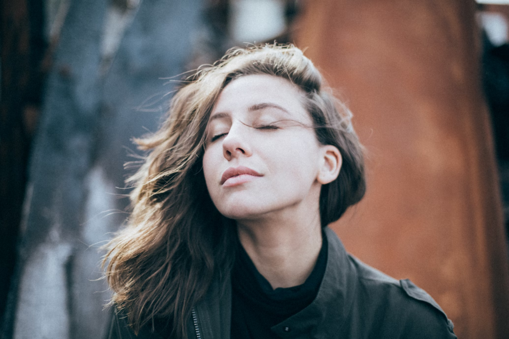 A woman with her eyes closed, seemingly enjoying a moment of peace or perhaps focusing on her senses. This serene expression can be used to illustrate the connection between smell loss and early Parkinson's disease symptoms.