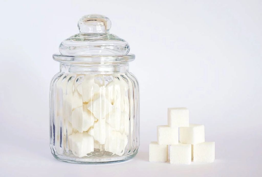Sugar cubes in a jar symbolize the high sugar content in soft drinks. Excessive consumption can negatively affect bone health by reducing calcium absorption, emphasizing the need for moderation to maintain strong bones.