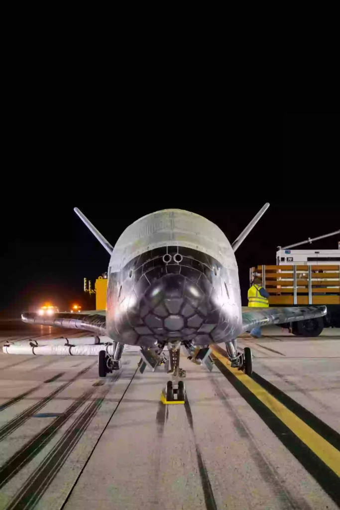 Front on image of X-37B spacecraft parked on the runway at night. 