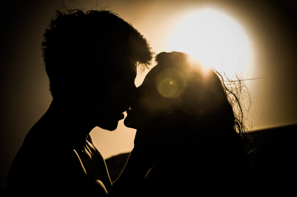 Silhouette of a couple kissing against sunset background, representing intimate contact that can transmit the herpes virus. Everyday expressions of affection like kissing may have unexpected connections to long-term brain health.