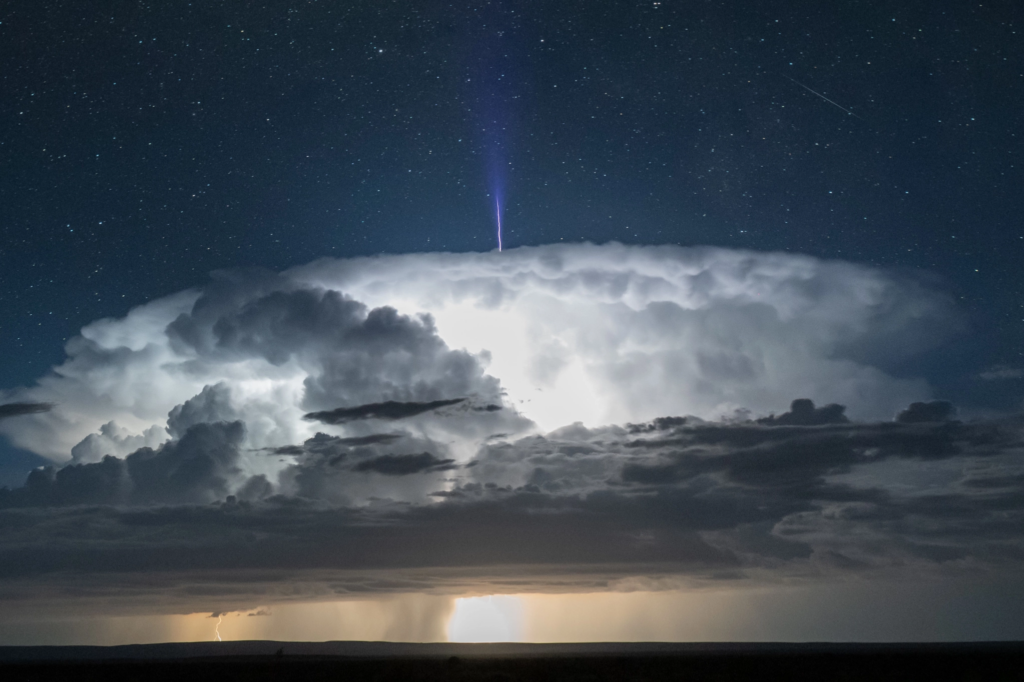 A blue jet emerges from a thunderhead storm cloud.