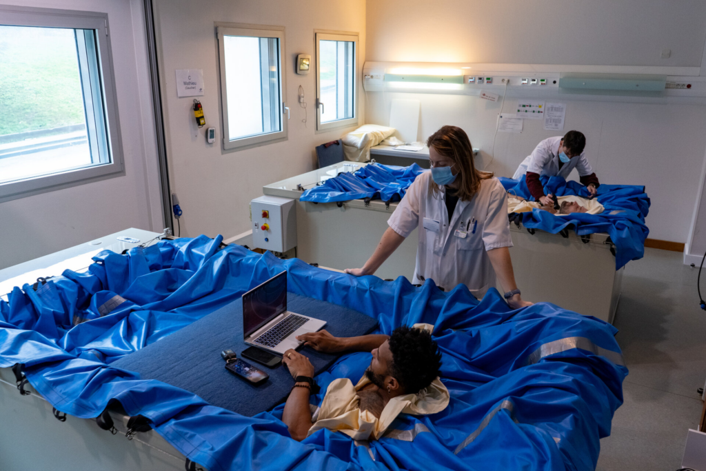 Nurses attend to volunteers who are lying in special beds to participate in The Space Agency volunteer offer study.