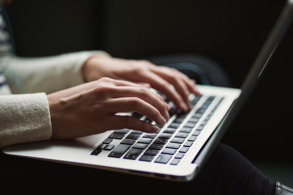 Close-up of hands typing on a laptop keyboard, depicting a user reviewing settings or researching alternatives after learning about the upcoming changes to Echo's privacy features.