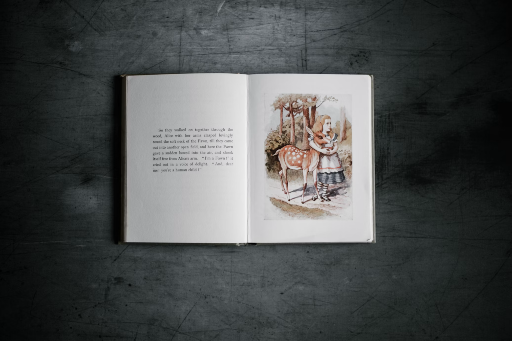 An open vintage book displaying an illustration from Lewis Carroll's classic tale, showing Alice in a striped dress standing beside a fawn in a forest setting. The book lies against a dark textured background. The visual storytelling captures the dreamlike quality that inspired Alice in Wonderland Syndrome.