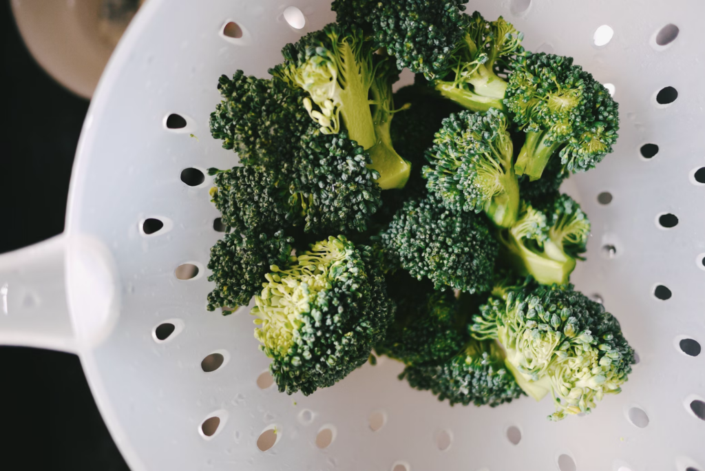 A colander filled with fresh broccoli, highlighting the importance of leafy greens in reducing cardiovascular disease risk.