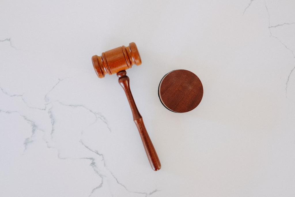 Wooden judge's gavel and sound block on marble surface.