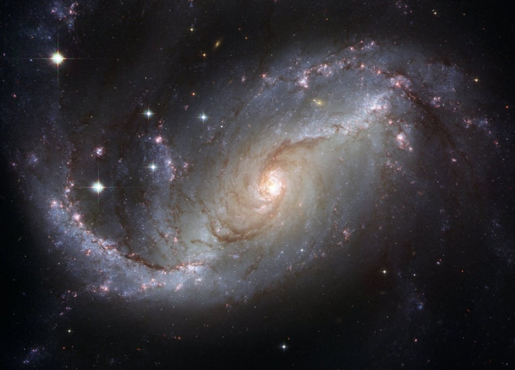 Spectacular spiral galaxy photographed in deep space, showing swirling star-filled arms with bright center and cosmic dust lanes against the blackness of the universe.