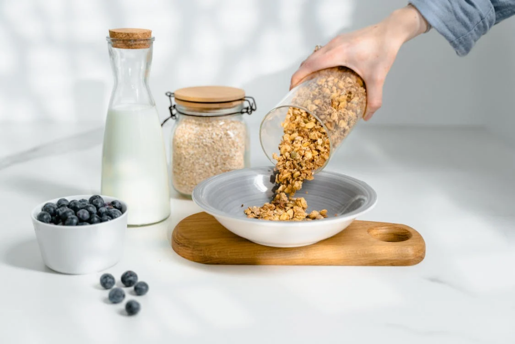 Person Pouring Cereals on Ceramic Bowl