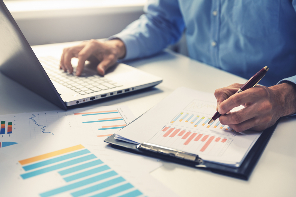 businessman analyzing annual business report with using laptop at office desk
