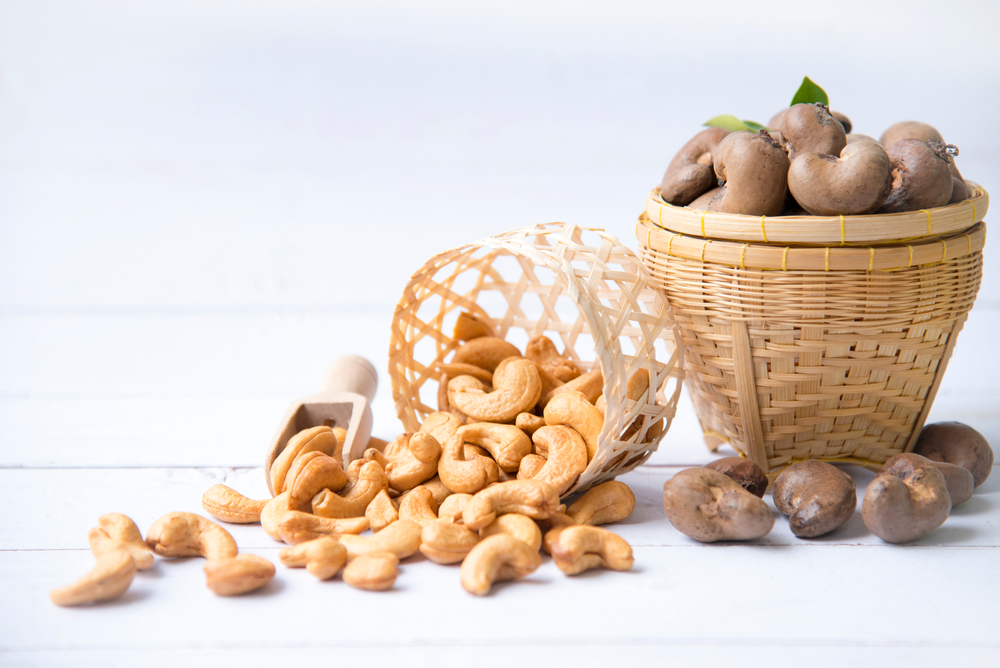 Roasted salted raw cashew nuts with Fresh cashew in spoon and basket isolated on white wooden background.

