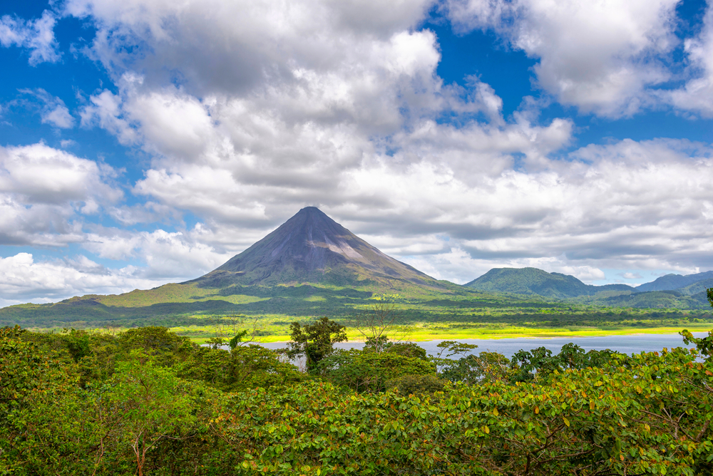 Amazing view of beautiful nature of Costa Rica with smoking volcano Arenal background. Panorama of volcano Arenal reflected on wonderful picturesque lake, La Fortuna, Costa Rica. Central America.
