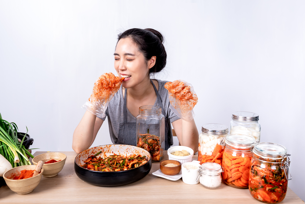 Portrait images of Korean attractive woman is eating Kimchi which she making, Kimchi which is a fermentation food preservation of Korean people consisting of many fresh vegetables and fruits
