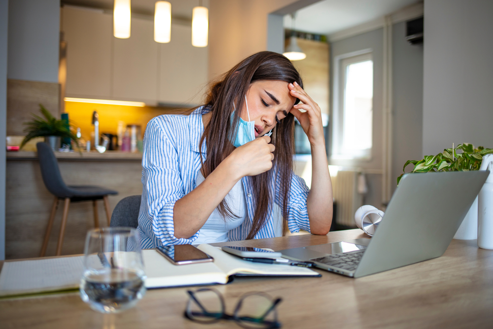 Woman working in the office and having difficulties breathing with face mask, she is pulling the mask down. The woman had to remove the mask to breathe after having to wear it for a long time
