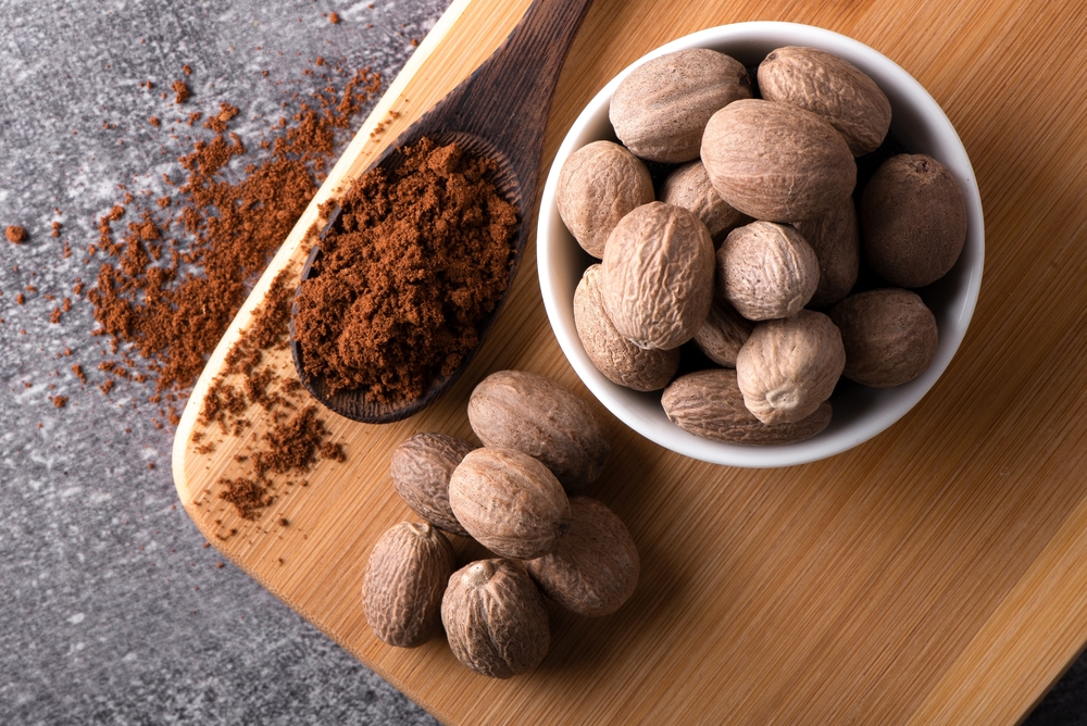 Nutmeg macro in a bowl. Nutmeg powder. Nutmeg spice in a wooden spoon.
