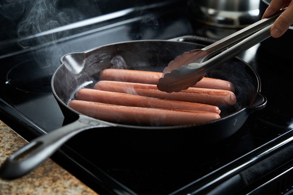 frying a hotdog in iron pan, prepares homemade hot dog
