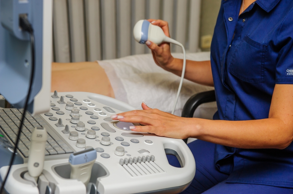 Medical specialists near ultrasound machine in the hospital ward.
