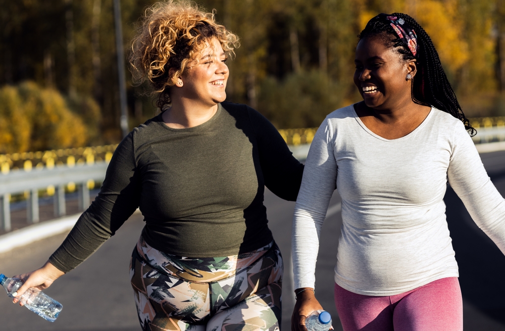 Two young plus size women jogging together.
