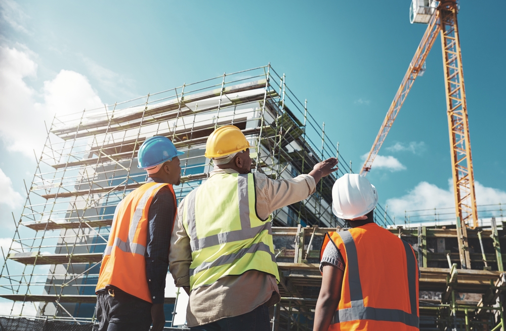 Engineering, construction site and team outdoor for building project, planning and architecture. Black woman and men contractor together for development and safety assessment discussion in city
