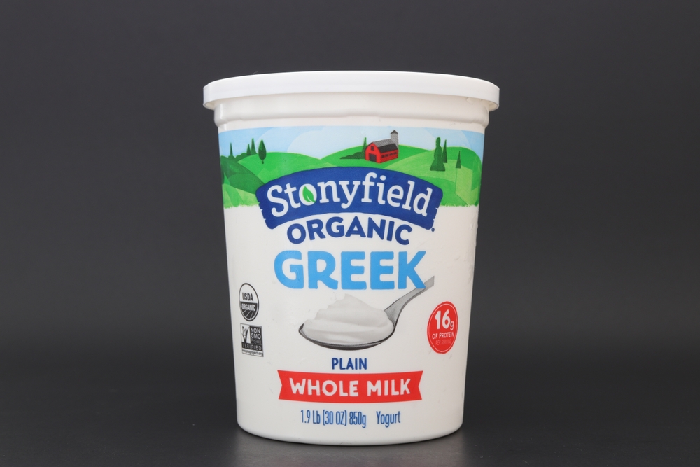 MIAMI, FLORIDA USA - 07-11-2023 Single container of Stonyfield whole milk organic greek yogurt isolated against dark background.