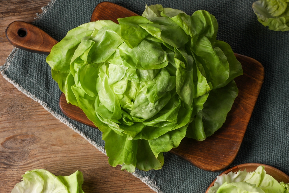 Fresh green butter lettuce on wooden table, flat lay