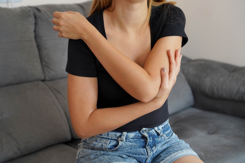 Muscle aches. Young woman has pain in arm muscles.
