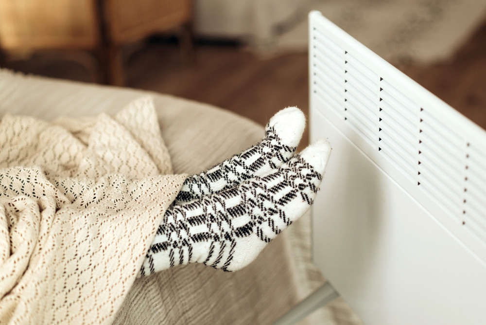 female feet in socks, in front of electric heater close up. cold heating season