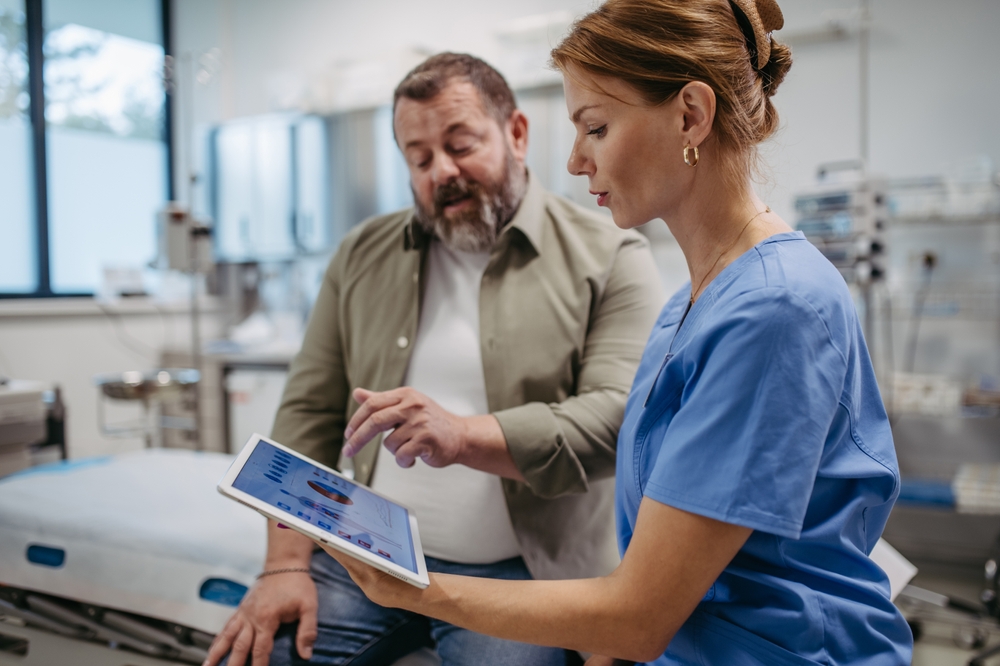 Female doctor consulting with overweight patient, discussing test result in doctor office. Obesity affecting middle-aged men's health. Concept of health risks of overwight and obesity.
