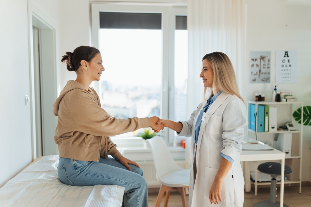 Teenage patient arriving at appointment with doctor, shaking hands with female pediatrician, physician. Teen girl have consultation, first visit with gynecologist. Concept of preventive health care
