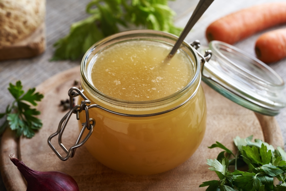 Chicken and vegetable soup or bone broth in a glass jar
