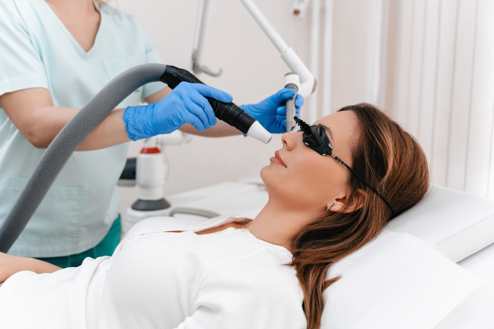 Beauty laser expert doing a cosmetic skin resurfacing treatment on a beautiful female patient. Modern and popular anti age procedure for removing old and stimulating new tissue creation.
