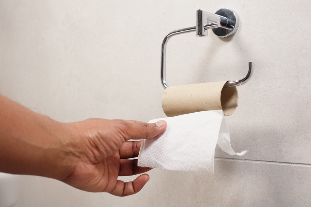 Hand pulling toilet paper roll in holder