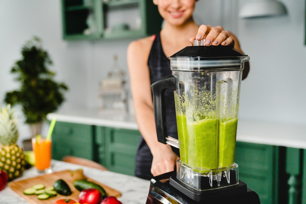 Close up photo of a girl making detox cocktail using blender in the kitchen. Smoothie and super food for healthy diet and eating habits. Vitamins and fiber source
