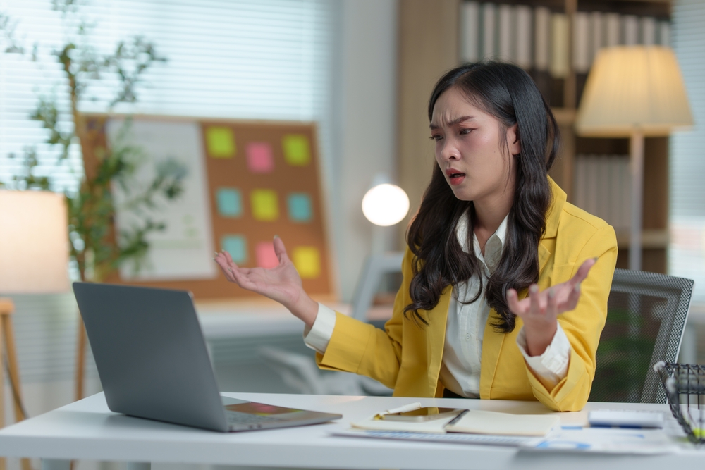 Stressed Asian businesswoman having headache in office with laptop financial business online marketing Irritability, tiredness with headaches or fatigue, drowsiness, office syndrome.

