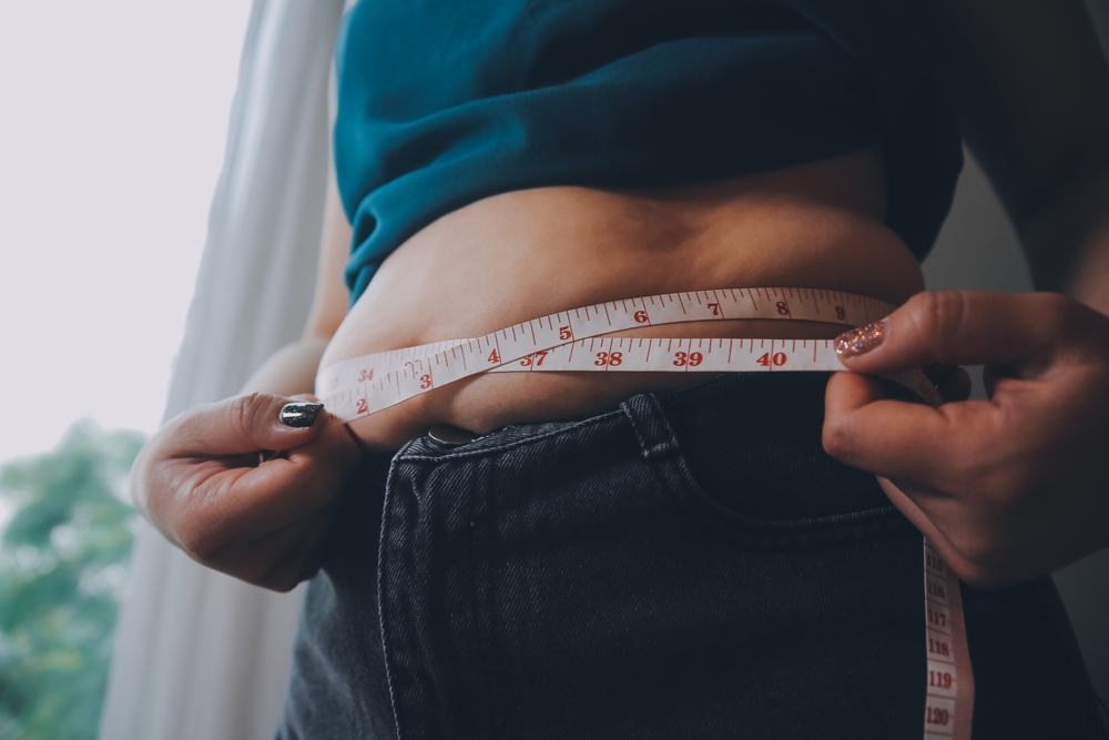 fat woman, fat belly, chubby, obese woman hand holding excessive belly fat with measure tape, woman diet lifestyle concept
