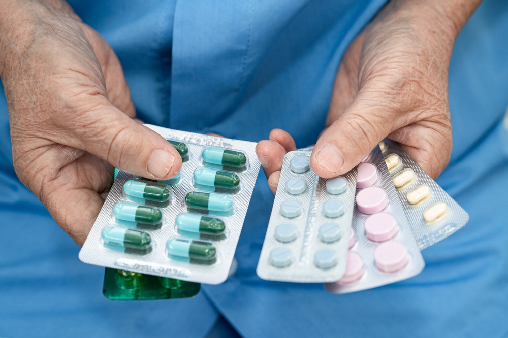 Asian senior woman patient holding antibiotics capsule pills for treatment infection patient in hospital, Pharmacy drugstore.