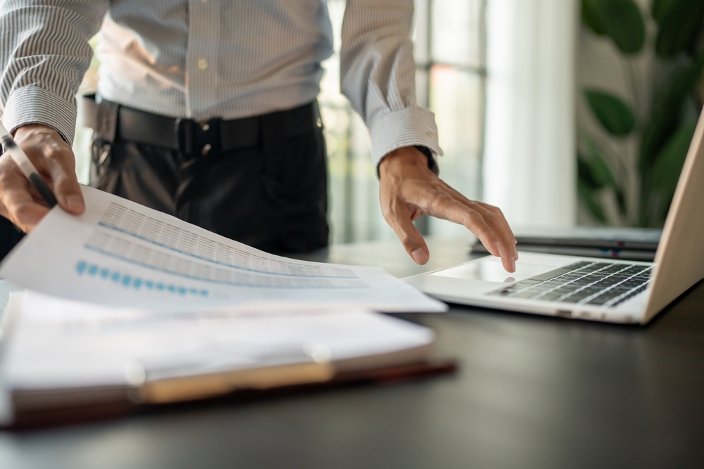 Businessman Accountant analyzing investment charts Invoice and pressing calculator buttons over documents. Accounting Bookkeeper Clerk Bank Advisor And Auditor
