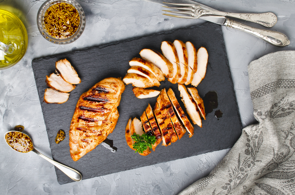Grilled chicken fillets on slate plate. Gray concrete background
