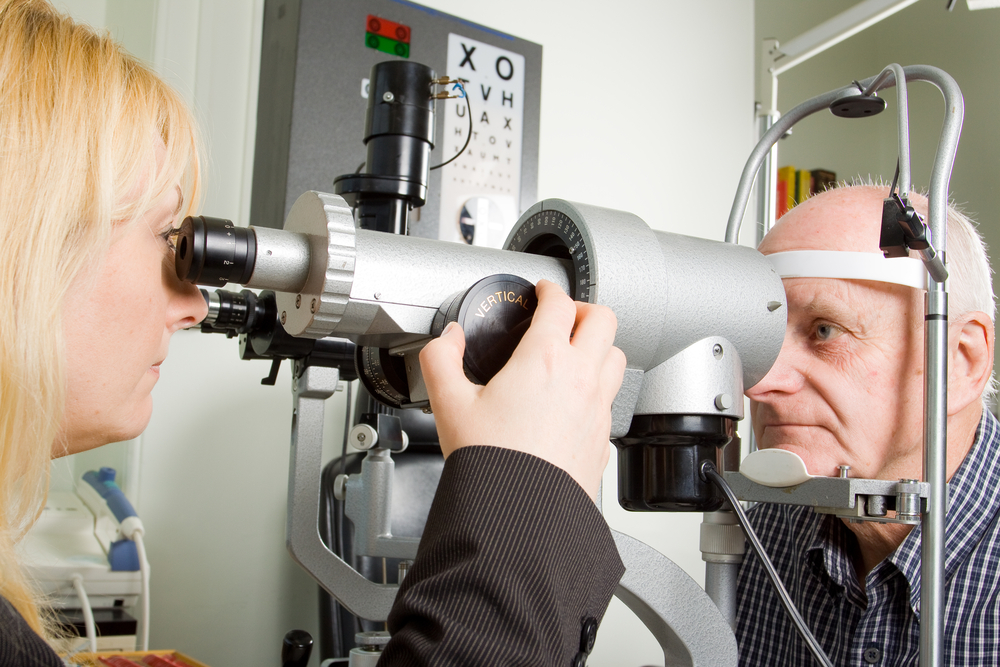 An older man taking an eye test examination at an opticians clinic
